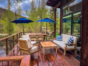 une terrasse en bois avec des chaises, des tables et des parasols dans l'établissement Rustic Modern Luxury Retreat with Hot Tub, à Ketchum
