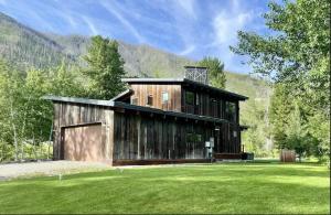 une grande maison en bois avec une cour verdoyante dans l'établissement Rustic Modern Luxury Retreat with Hot Tub, à Ketchum