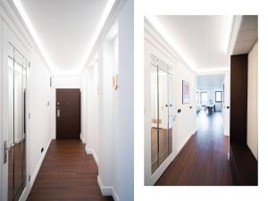 a hallway with white walls and a door and a hallway with wood floors at Suite Sixteen Szafarnia in Gdańsk