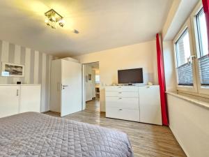 a bedroom with a bed and a flat screen tv at Mienhus Apartments Ferienwohnung Famke in Norden