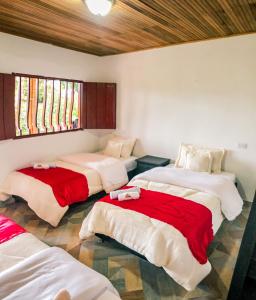 a room with four beds with red and white sheets at Hostal y Restaurante Lujans in San Agustín