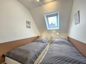 two beds in a small room with a window at Mienhus Apartments Ferienwohnung Jantje in Norden