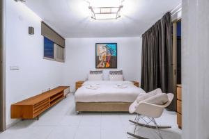 um quarto com uma cama e uma cadeira em Penthouse Mapu - Mamad em Tel Aviv