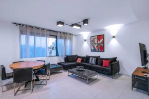 uma sala de estar com um sofá e uma mesa em Penthouse Mapu - Mamad em Tel Aviv