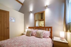 a bedroom with a bed with pink sheets and pillows at Gunn Cottage - Dog-friendly enclosed garden in Santon Bridge
