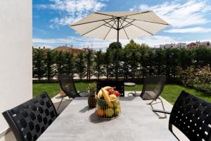 - une table avec une corbeille de fruits et un parasol dans l'établissement Costa Premium, à Funtana