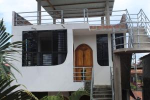 une maison blanche avec une porte en bois et des escaliers dans l'établissement Departamento a 3 cuadras de la plaza principal, à Puerto Maldonado
