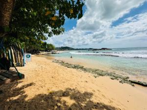 a sandy beach with people swimming in the ocean at Royal Palace Mirissa in Mirissa