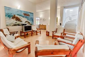 un soggiorno con sedie, TV e scale di Hotel Al Faro a San Teodoro