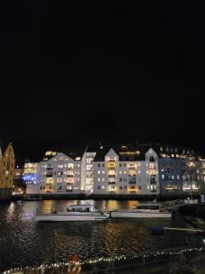 Single Elegant Room i sentrum- Sea View في أوليسوند: مدينة في الليل فيها مباني وقوارب في الماء