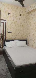 Ce lit se trouve dans une chambre dotée de draps blancs et d'un mur. dans l'établissement HOTEL BLUE MOON, à kolkata