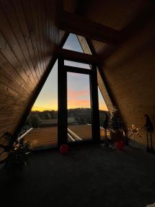 ein Fenster in einem Zimmer mit Blick auf den Sonnenuntergang in der Unterkunft Azalea Chalet in Divčibare