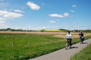 dwoje ludzi jeżdżących rowerami na ścieżce w pobliżu pola w obiekcie Appartementhaus auf Moenchgut w mieście Thiessow