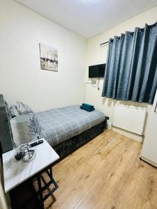 Kleines Zimmer mit einem Bett und einem Tisch in der Unterkunft AJB INTERNATIONAL LTD in London