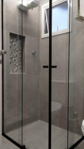 La salle de bains est pourvue d'une douche avec une porte en verre. dans l'établissement Aps de frente com sacada ou terraço a 10 minutos do Aeroporto, à Porto Alegre