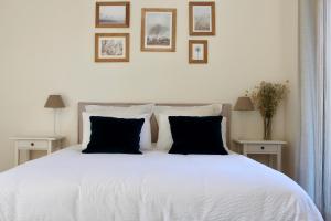 a bedroom with a white bed with black pillows at MAISON MOZ entre Chambord & Cheverny in Fontaines-en-Sologne