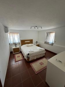 ein kleines Schlafzimmer mit einem Bett und zwei Fenstern in der Unterkunft Casa do Terreiro in São João de Tarouca