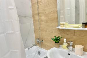 ein Badezimmer mit einem weißen Waschbecken und einer Dusche in der Unterkunft G-home apartments in Expo New life-2 in Astana