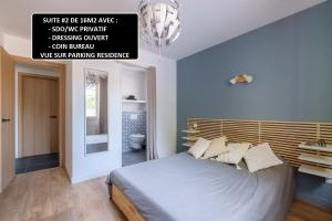 a bedroom with a large bed and a sign on the wall at BEL APPARTEMENT 3 SUITES AVEC Wc SDO PRIVATIFS - CUISINE COMMUNE in Tassin-la-Demi-Lune