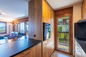 a kitchen with wooden cabinets and a living room at Arnica 1 - 6 pers - piscine in Nendaz
