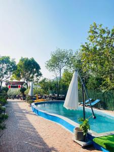 een leeg zwembad met een parasol en stoelen bij An Homestay Tam Coc in Ninh Binh