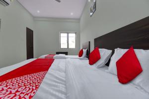 a bedroom with a large bed with red and white pillows at OYO OMWAY HOTEL in Jaipur