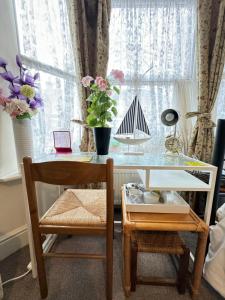 a desk with a chair and a table with flowers in a window at Big Private Room In Town Centre in Eastleigh