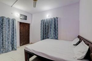 a bedroom with a bed with blue curtains and a door at Gracious Guest House in Lucknow