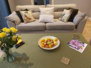 una sala de estar con una mesa con un bol de fruta en Rose Garden Retreat, en Rayleigh