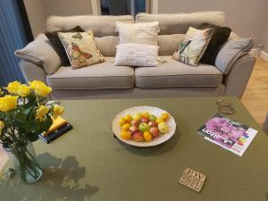 a living room with a table with a bowl of fruit at Rose Garden Retreat in Rayleigh