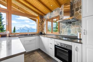 a kitchen with white cabinets and a large window at Les 4 Abeilles - 6 pers - bien amenage in Nendaz