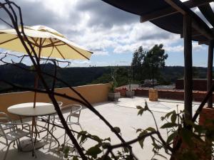 une terrasse avec une table, des chaises et un parasol dans l'établissement Pousada Casa Jardim, à Serra Negra