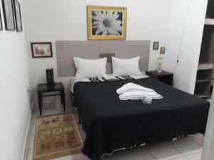 a bedroom with a bed with a black and white blanket at Pousada Casa Jardim in Serra Negra