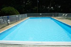 une grande piscine bleue avec un terrain de volley-ball dans l'établissement Clinton Motel, à Clinton