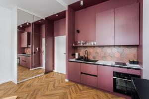 a kitchen with purple cabinets and wooden floors at Very Berry - Kochanowskiego 6/4 - Jeżyce, self check in 24h in Poznań