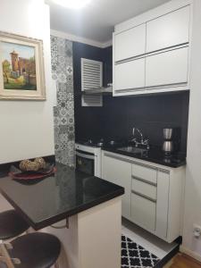 a kitchen with white cabinets and a black counter top at Century Hall in Curitiba