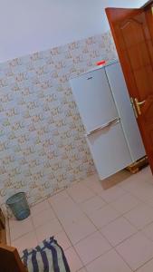 een keuken met een koelkast en een tegelwand bij Guest house AKPAKPA in Cotonou