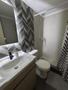 y baño con lavabo, aseo y espejo. en Condominio Yucatán Iquique en Iquique
