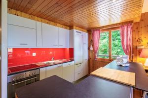 uma cozinha com armários brancos e uma parede vermelha em Chaedoz 45 - 7 pers - au calme em Nendaz