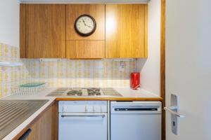 eine Küche mit einer Uhr an der Wand über einem Herd in der Unterkunft Panoramic E6 - 4 pers - pres des pistes in Nendaz
