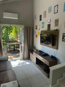 a living room with a television and a table at Villa Cabanas - Pé na areia in Governador Celso Ramos