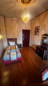een slaapkamer met een bed, een bureau en een kroonluchter bij Hotel & Restaurant Com Viet in Oschatz