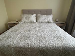 1 cama con edredón blanco y 2 almohadas en Condominio Yucatán Iquique en Iquique