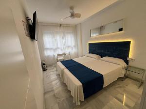 1 dormitorio con 1 cama con manta azul y blanca en Hospederia Imar, en Cádiz