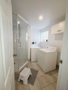 uma casa de banho branca com um chuveiro e um lavatório. em Cozy 1BR in Vieux-Longueuil +parking 14min Downtown em Longueuil
