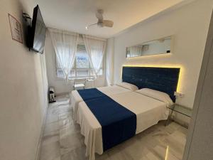 sypialnia z łóżkiem z niebiesko-białym kocem w obiekcie Apartamentos Turisticos Imar w Kadyksie