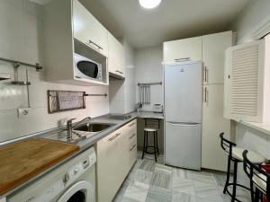 Biała kuchnia ze zlewem i lodówką w obiekcie Apartamentos Turisticos Imar w Kadyksie