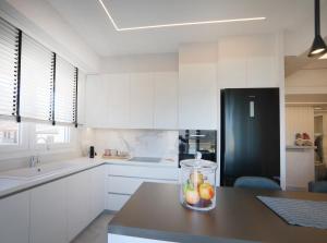 uma cozinha com armários brancos e um frigorífico preto em Sam Casa Luxury Living em Castória