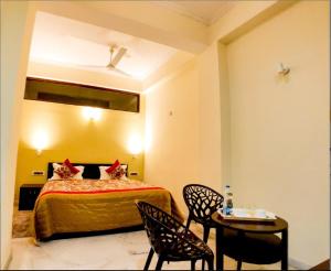 1 Schlafzimmer mit einem Bett, 2 Stühlen und einem Tisch in der Unterkunft Narmade river view resort & restaurant in Hoshangābād