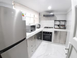 Il comprend une cuisine blanche équipée d'une cuisinière et d'un réfrigérateur. dans l'établissement APARTAMENTO LINDO - A 2 Cuadras de la Plaza de Armas y del Palacio de Gobierno, à Lima